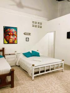 1 dormitorio con cama blanca y almohadas azules en Hotel Villa Ivel, en Turbaco