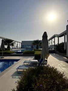 un complejo con sillas, sombrilla y piscina en Luxury Beachfront Studio Apartment Marjan Island en Ras al-Jaima