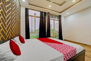 a bedroom with a bed with red pillows and a window at Vachan Garden And Resort in Bhopal