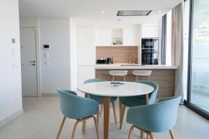 een keuken met een witte tafel en blauwe stoelen bij El Sol Higueron West Apartment in Fuengirola
