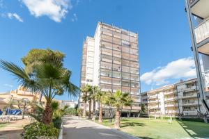 um edifício alto com palmeiras em frente a uma rua em Apartamento perfecto en Sitges em Sitges