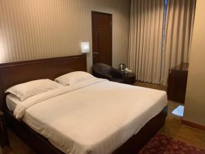 a bedroom with a large bed and a chair at ENHAII HOTEL in Bandung
