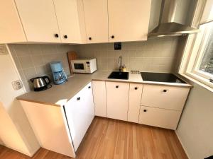 una pequeña cocina con armarios blancos y microondas en Vakantiebungalow Vrijzicht en Kortgene