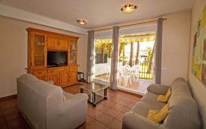 uma sala de estar com um sofá e uma televisão em Adosado familiar con piscina - Palm Beach 40 ALBERT VILLAS em Alcossebre