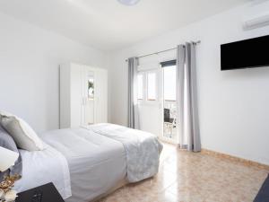 a white bedroom with a bed and a flat screen tv at EK Los Eucaliptos Fasnia in Fasnia