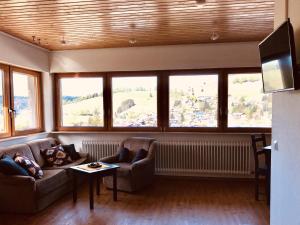 a living room with two couches and a table and windows at Gästehaus Kehrwieder in Todtnau