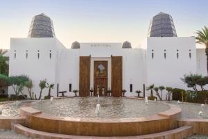 Sofitel Agadir Royal Bay Resort في أغادير: مبنى ابيض كبير وامامه نافورة