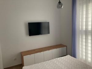 a bedroom with a bed and a flat screen tv on the wall at Apartament Berlinek in Grzybowo