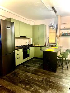a kitchen with green cabinets and a black refrigerator at Q Green and Comfy place near Palas in Iaşi