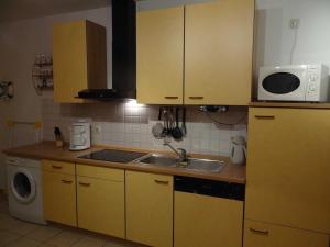 a kitchen with yellow cabinets and a sink and a microwave at Fewo Fiete in Trassenheide
