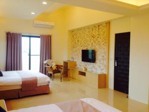una camera d'albergo con letto, scrivania e TV di Sweetlight B&B a Jiaoxi