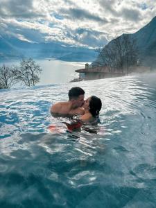 Ein Mann und eine Frau küssen sich im Wasser in der Unterkunft Esprit D'Hotel Panoramico in Fonteno