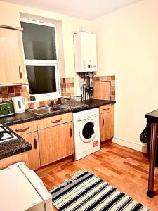 cocina con fregadero y lavadora en Peaceful park side apartment en Hastings