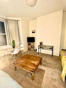 a living room with a couch and a table at Peaceful park side apartment in Hastings