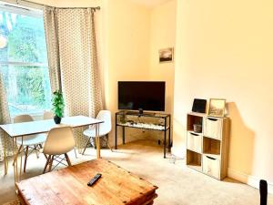 een woonkamer met een tafel en een televisie bij Peaceful park side apartment in Hastings