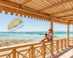 a woman sitting on a deck looking out at the beach at Dolphin house in Hurghada