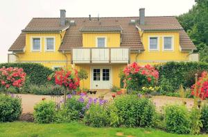 a yellow house with flowers in front of it at Ferienwohnung Storchennest in Neuendorf am See
