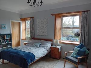 a bedroom with a bed and a chair and a window at BARHOLM CROFT Holiday Cottage in Creetown