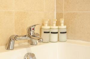 a bathroom sink with three bottles of soap at The Corner Stop~ Dog Friendly Holiday Let in Plymouth in Plymouth