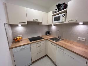 cocina con armarios blancos, fregadero y microondas en Appartements Achensee en Maurach