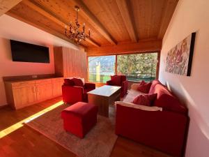 uma sala de estar com mobiliário vermelho e uma televisão de ecrã plano em Appartements Achensee em Maurach