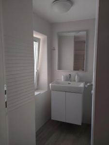 a white bathroom with a sink and a mirror at Studio Nikola in Baška