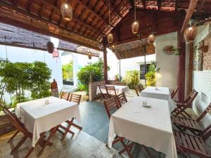 un restaurante con mesas y sillas blancas y ventanas en Trendy Life Villa en Hoi An