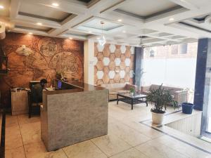 a lobby with a man sitting at a desk in a room at Hotel Tej Plaza Near IGI Airport in New Delhi