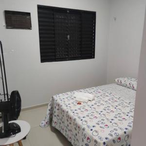 a room with a bed and a window and a table at Lugar para chamar de seu in Teresina