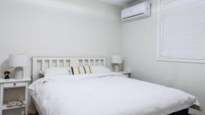 a white bedroom with a white bed and a window at Rye's Get Away in Rye