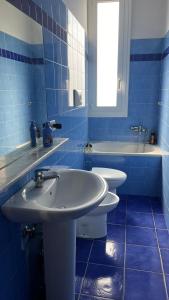 - une salle de bains carrelée de bleu avec deux lavabos et une baignoire dans l'établissement Daeiouz II, à Milan
