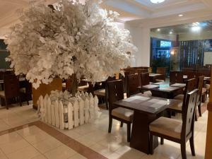 a dining room with tables and a large tree at ENHAII HOTEL in Bandung