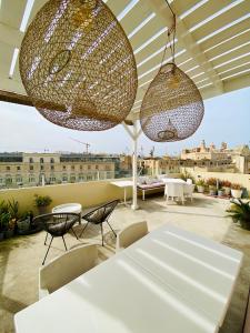 a patio with white tables and chairs and lights at Nelli's B&B in Cospicua