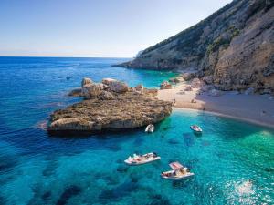 twee boten in het water naast een strand bij Margaida Boutique Hotel & SPA in Cala Gonone