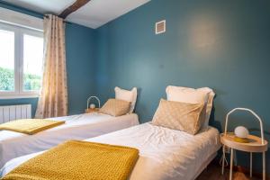 two beds in a room with blue walls at L'Îlot Pomme Cottage in Campigny