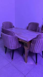 a wooden table with two purple chairs around it at Delight Bay Shortlet in Lekki