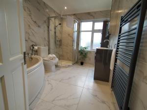 a bathroom with a tub and a toilet and a sink at Sirius House - sleeps 7, driveway, garden in Crewe