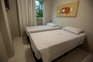 two beds in a small room with a window at Várzea HOTEL in Sobral