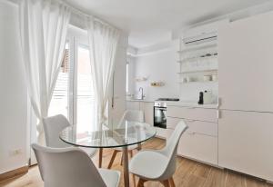 a white kitchen with a glass table and chairs at Casa Dolce Casa in Rome
