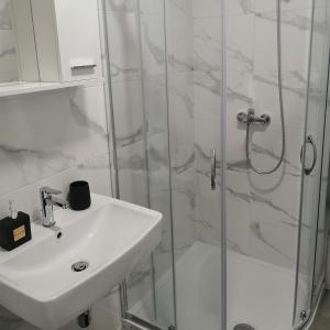 ein weißes Bad mit einem Waschbecken und einer Dusche in der Unterkunft Apartman 33 in Banja Luka