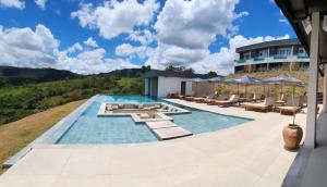 a swimming pool with lounge chairs and a house at Serrano Exclusive in Tiradentes