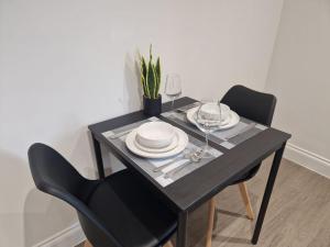 a black dining room table with plates and wine glasses at Wakefield Getaway - Cosy Apt with Free Parking in Wakefield