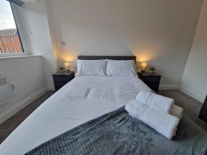 una camera da letto con un grande letto con lenzuola e cuscini bianchi di Wakefield Getaway - Cosy Apt with Free Parking a Wakefield