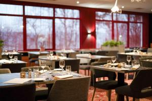 un restaurante con mesas y sillas y copas de vino en Silva Hotel Spa-Balmoral en Spa