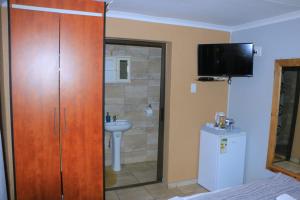 a bathroom with a wooden closet and a sink at ZWIZWO Guest House in Thohoyandou