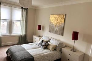 um quarto com uma cama e 2 candeeiros e janelas em Stylish & Central Flat in Edinburgh. Free Parking em Edimburgo