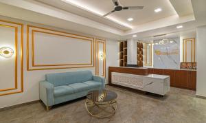 Treebo Trend Global Stay Jayanagar في بانغالور: غرفة معيشة مع أريكة زرقاء وطاولة