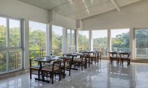 Treebo Trend Global Stay Jayanagar في بانغالور: غرفة كبيرة بها طاولات وكراسي ونوافذ