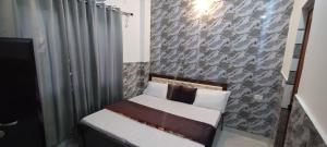 a small bed in a room with a stone wall at Stay With Prarambha in Rishīkesh