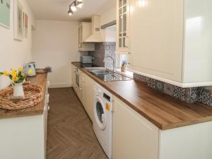 a kitchen with white cabinets and a washer and dryer at Cosy Cottage in Morpeth